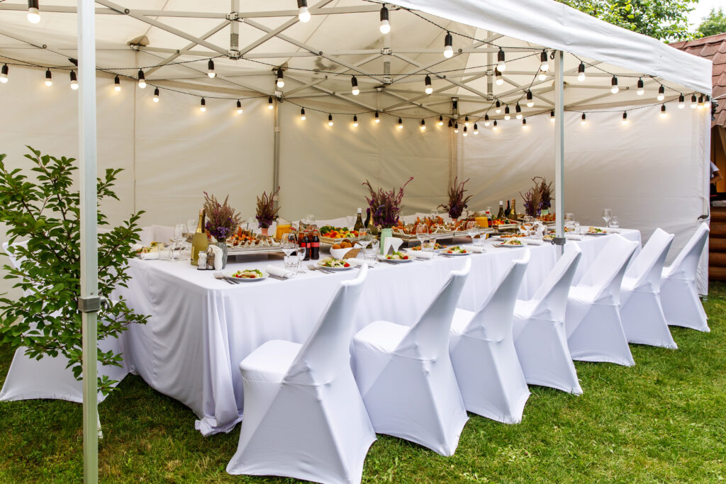 | Wedding white tent with white chairs. Banquet hall under a tent for wedding or another catered event dinner